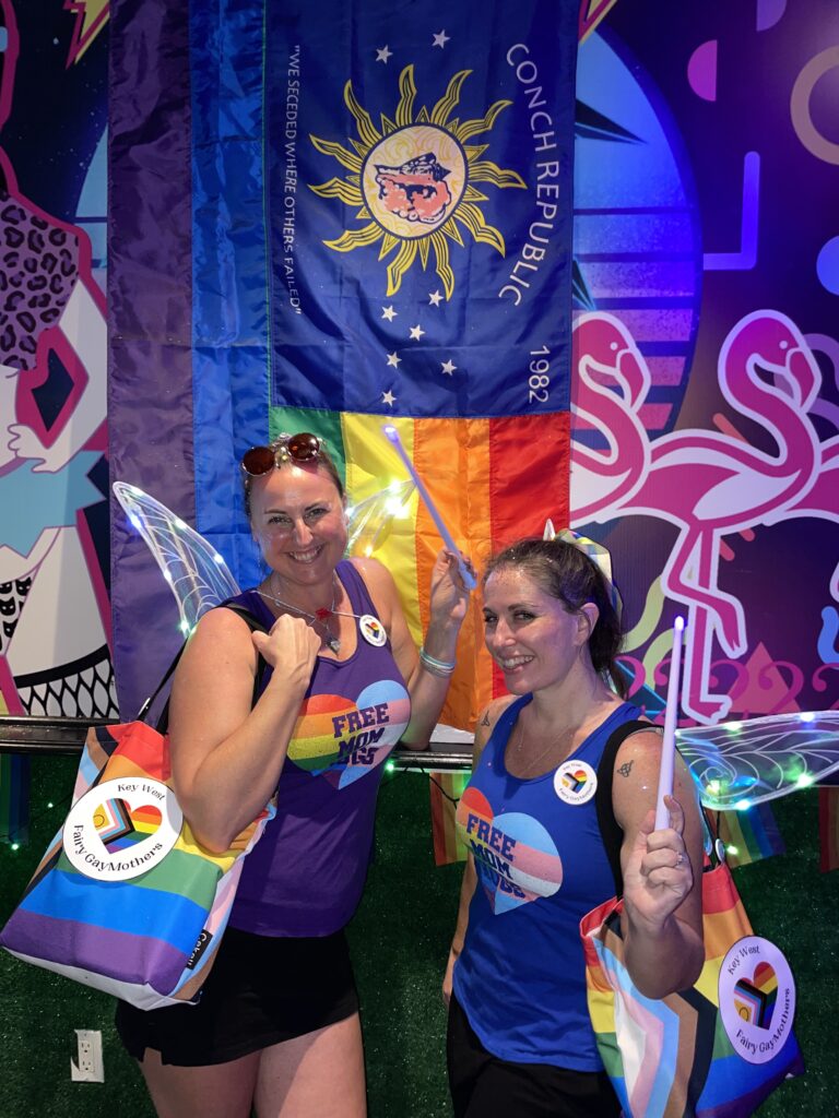 Fairy GayMothers Claire and Serena in front of the Conch Republic Pride flag